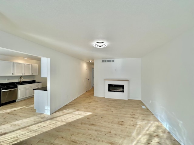 unfurnished living room with light hardwood / wood-style floors and sink