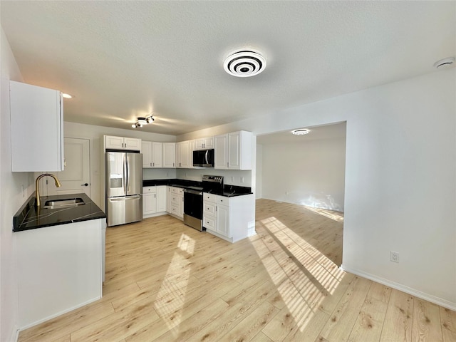 kitchen with a textured ceiling, white cabinetry, stainless steel appliances, sink, and light wood-type flooring