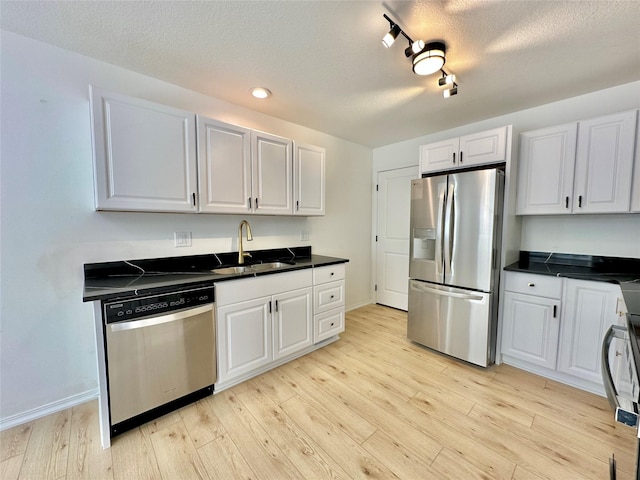 kitchen with light hardwood / wood-style flooring, appliances with stainless steel finishes, sink, white cabinetry, and a textured ceiling