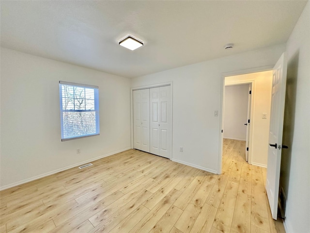 unfurnished bedroom with a closet and light wood-type flooring