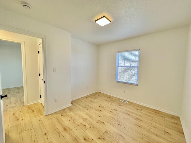 unfurnished room featuring light wood-type flooring and a textured ceiling