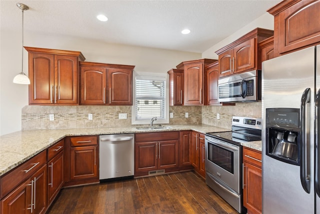 kitchen with visible vents, a sink, dark wood finished floors, light stone countertops, and stainless steel appliances