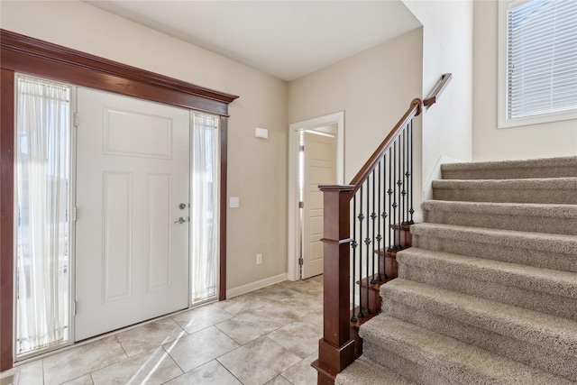 entrance foyer featuring stairway, light tile patterned flooring, and a healthy amount of sunlight