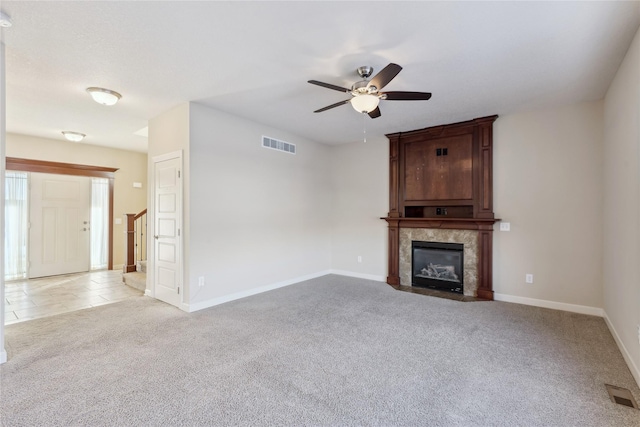 unfurnished living room featuring a high end fireplace, light carpet, a ceiling fan, and visible vents