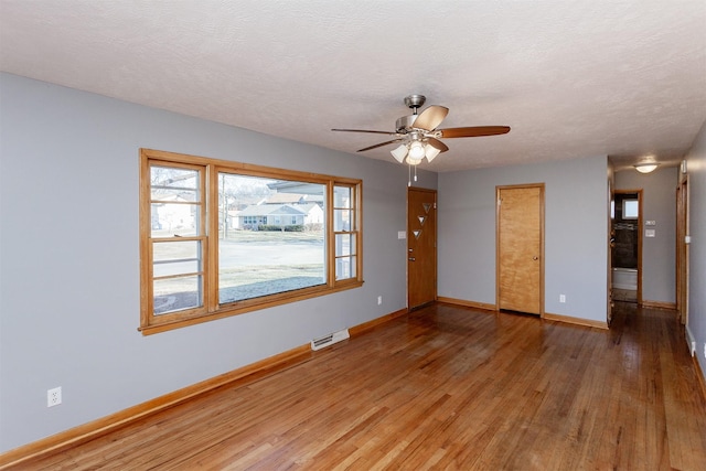 empty room with wood-type flooring, a textured ceiling, and ceiling fan