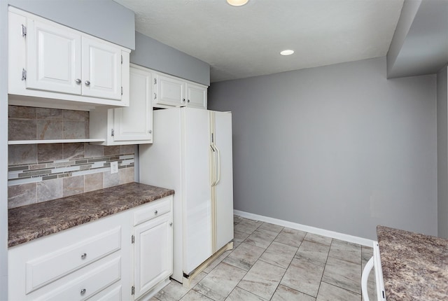 kitchen featuring backsplash, white cabinets, white refrigerator, and light tile patterned flooring