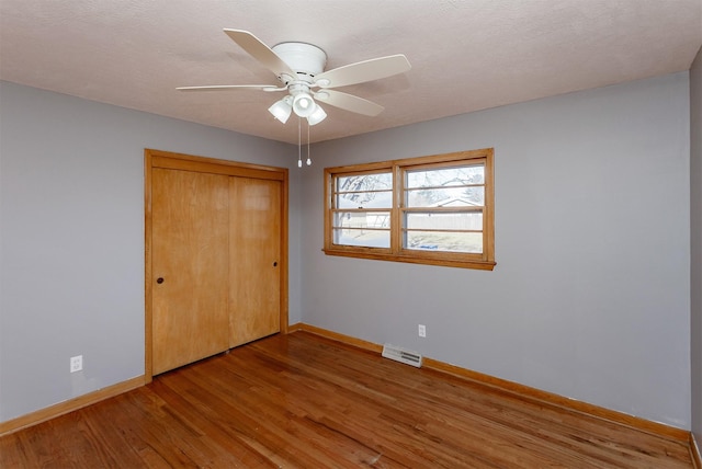 unfurnished bedroom featuring ceiling fan, wood-type flooring, and a closet