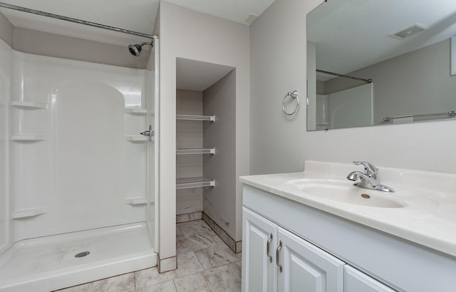 bathroom featuring walk in shower and vanity