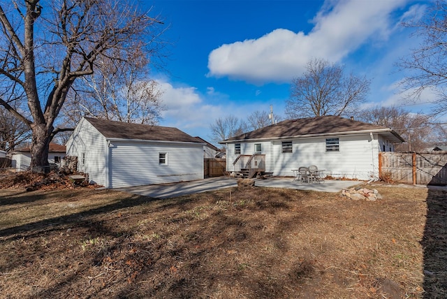 rear view of property featuring an outdoor structure, a patio, and a yard