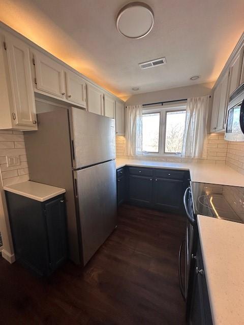 kitchen with dark wood-type flooring, backsplash, range with electric cooktop, white cabinets, and white fridge