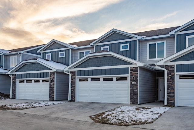 view of front of property with an attached garage, stone siding, board and batten siding, and concrete driveway