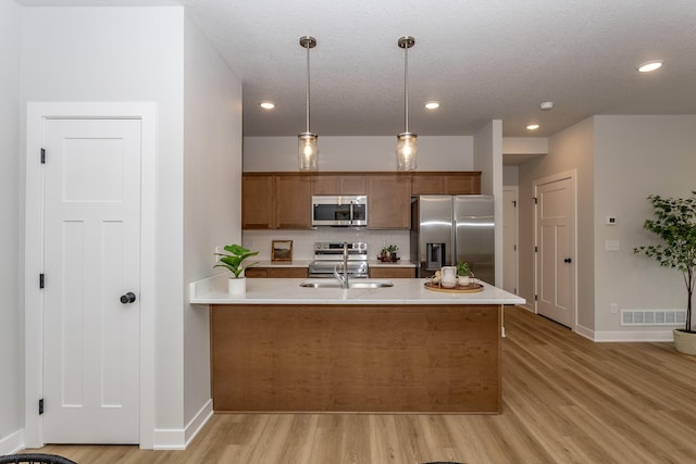 kitchen with visible vents, hanging light fixtures, a peninsula, stainless steel appliances, and light countertops