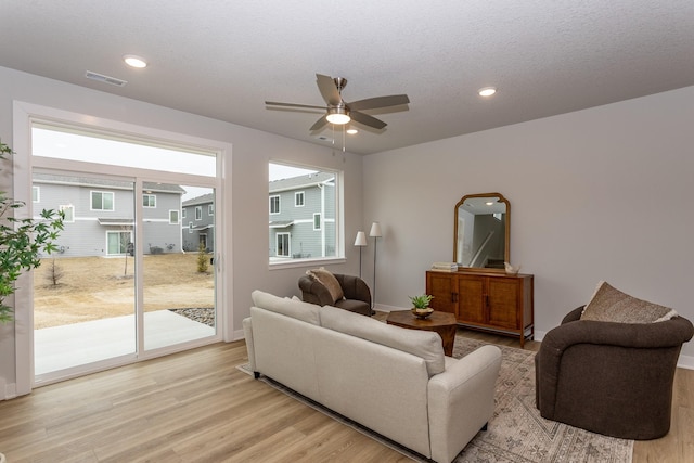 living room with visible vents, a ceiling fan, a textured ceiling, light wood-type flooring, and recessed lighting