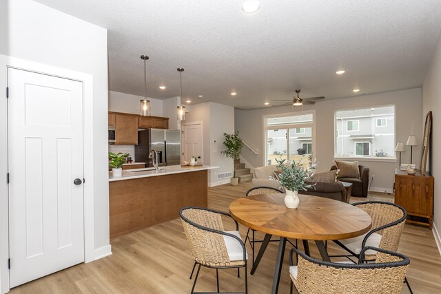 kitchen featuring appliances with stainless steel finishes, white cabinets, hanging light fixtures, ceiling fan, and light hardwood / wood-style flooring