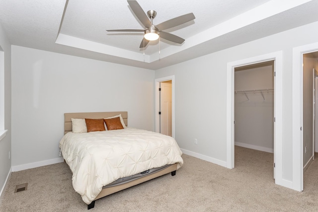 bedroom featuring light carpet, baseboards, visible vents, and a raised ceiling