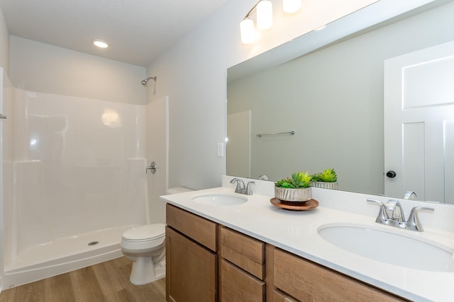 full bath featuring a shower, a sink, toilet, and wood finished floors