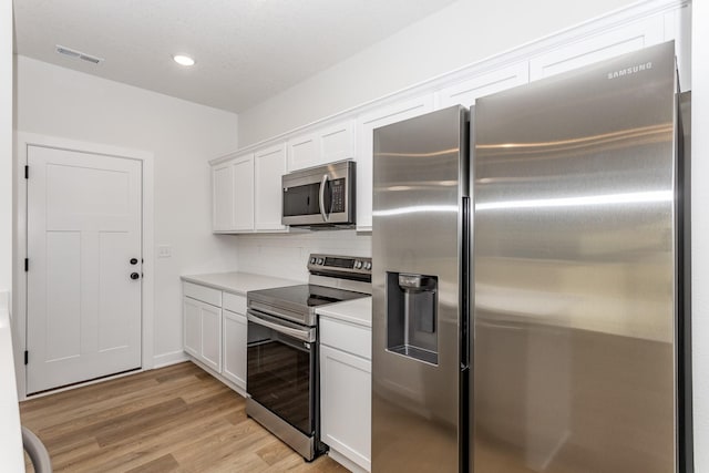 kitchen featuring white cabinetry, backsplash, light hardwood / wood-style flooring, and appliances with stainless steel finishes