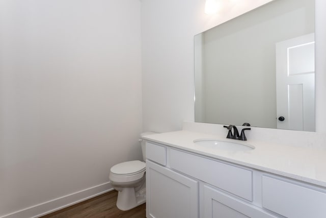 bathroom with wood-type flooring, toilet, and vanity