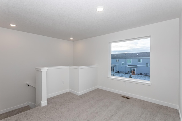 carpeted spare room featuring a textured ceiling