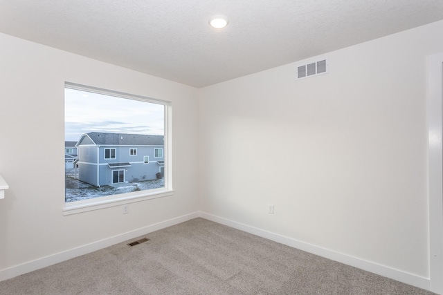 carpeted spare room featuring a textured ceiling