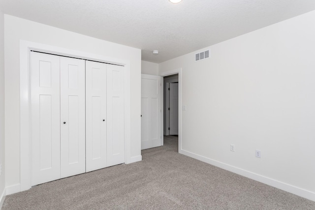 unfurnished bedroom featuring light colored carpet, a closet, and a textured ceiling