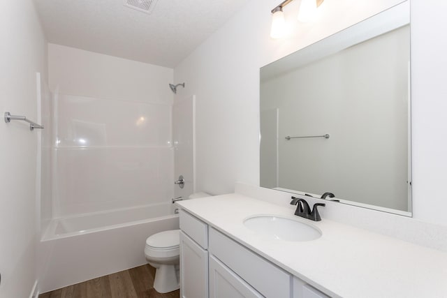 full bathroom with hardwood / wood-style floors, vanity,  shower combination, toilet, and a textured ceiling