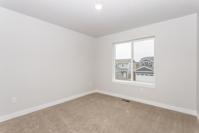 empty room with carpet, visible vents, and baseboards