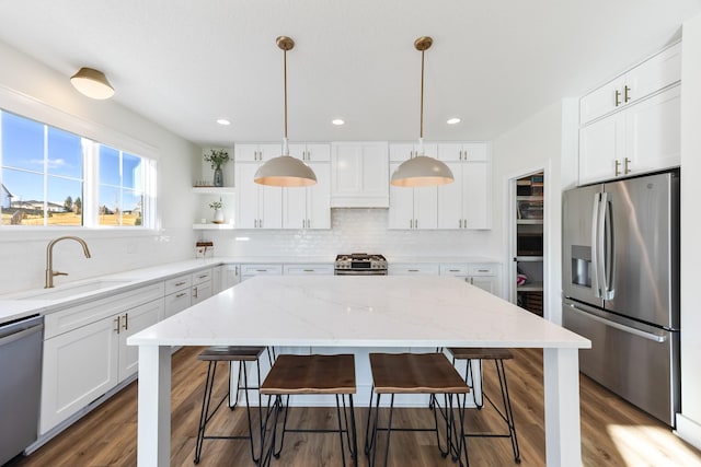 kitchen with stainless steel appliances, a kitchen bar, hanging light fixtures, and white cabinets