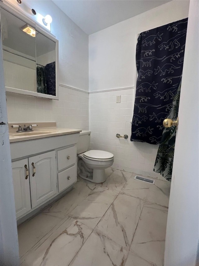 bathroom with vanity, tile walls, and toilet