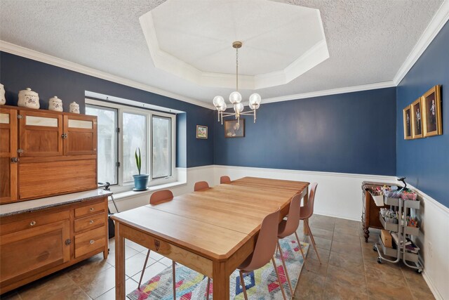 dining room with an inviting chandelier, a raised ceiling, ornamental molding, and a textured ceiling