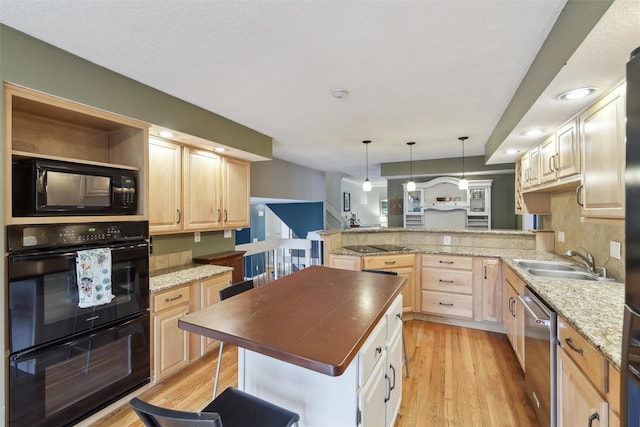 kitchen with light wood finished floors, a peninsula, light brown cabinetry, a sink, and black appliances