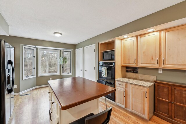 kitchen with baseboards, light wood-style floors, black appliances, and light brown cabinetry