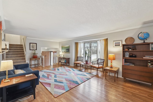 living room featuring stairs, a textured ceiling, wood finished floors, and ornamental molding