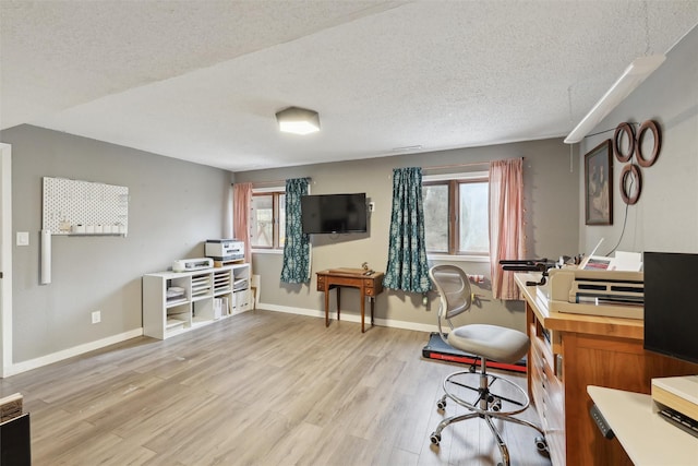 home office featuring light wood finished floors, a textured ceiling, and baseboards