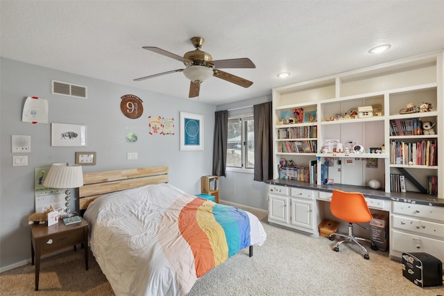 bedroom featuring visible vents, baseboards, light colored carpet, ceiling fan, and built in study area