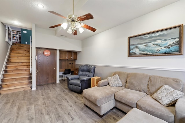 living area featuring light wood finished floors, built in desk, stairs, and ceiling fan