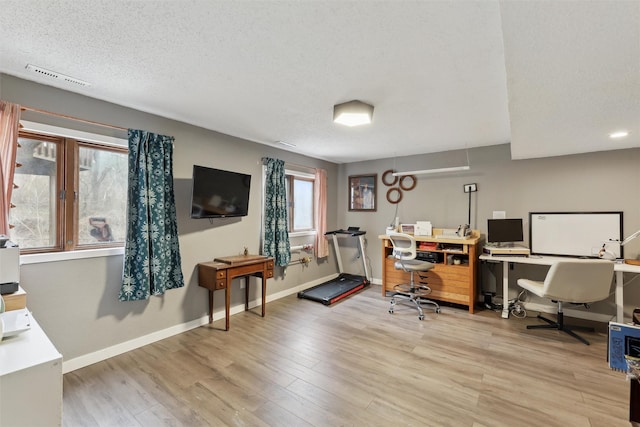 office area with visible vents, a textured ceiling, baseboards, and wood finished floors