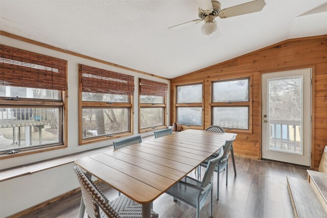 dining room with wooden walls, ceiling fan, lofted ceiling, and wood finished floors