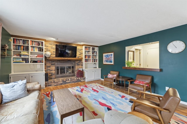 living room with a brick fireplace, built in features, wood finished floors, and baseboards