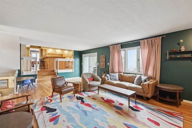 living area with light wood-type flooring, baseboards, and a textured ceiling