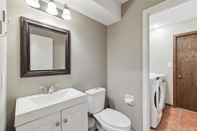 half bath featuring vanity, toilet, tile patterned flooring, and washing machine and clothes dryer