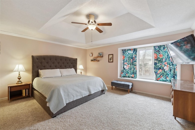 carpeted bedroom featuring baseboards, a raised ceiling, a ceiling fan, and crown molding