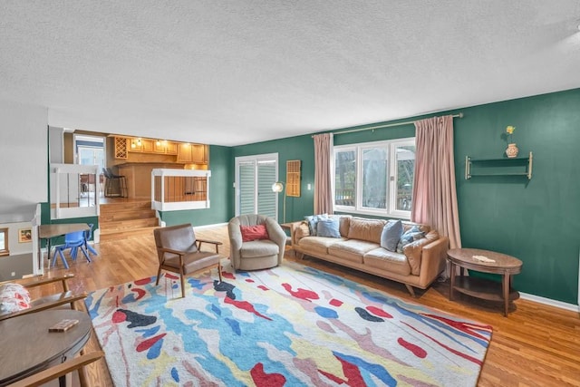 living area with a wealth of natural light, a textured ceiling, and light wood finished floors
