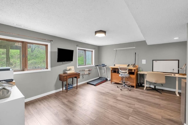 home office featuring wood finished floors, a textured ceiling, baseboards, and visible vents