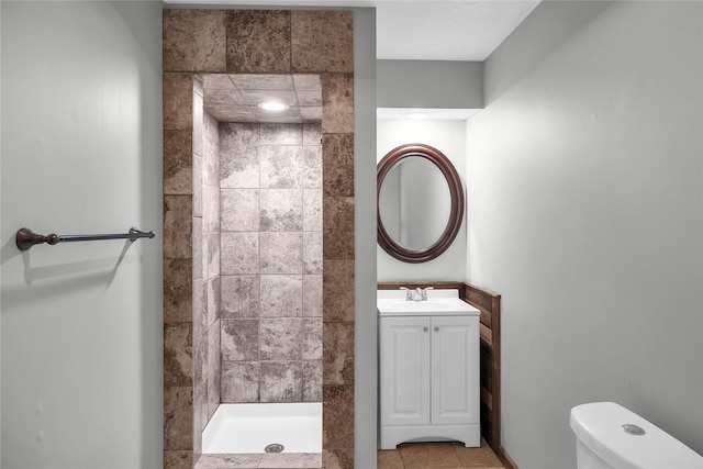 bathroom featuring toilet, vanity, tile patterned floors, and tiled shower
