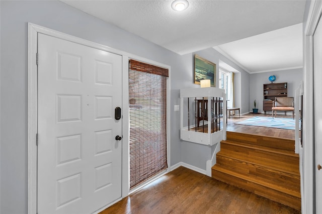 entrance foyer featuring a textured ceiling, dark wood-style flooring, baseboards, stairway, and ornamental molding