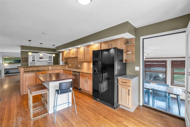 kitchen featuring stainless steel dishwasher, black refrigerator with ice dispenser, light wood-type flooring, pendant lighting, and a peninsula