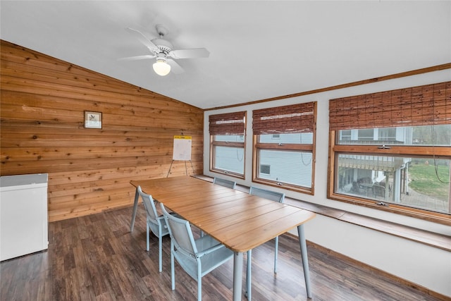 dining area with dark wood-style floors, lofted ceiling, a ceiling fan, and wooden walls