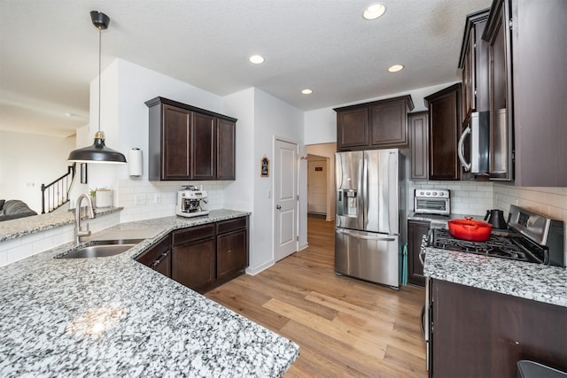 kitchen with light wood-type flooring, dark brown cabinetry, stainless steel appliances, and a sink