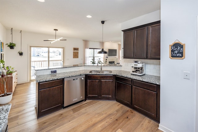 kitchen featuring dark brown cabinetry, light wood finished floors, decorative backsplash, stainless steel dishwasher, and a sink